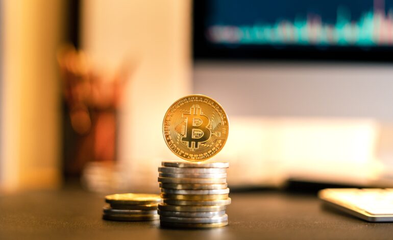 Bitcoin is placed on a desk in front of a computer graph